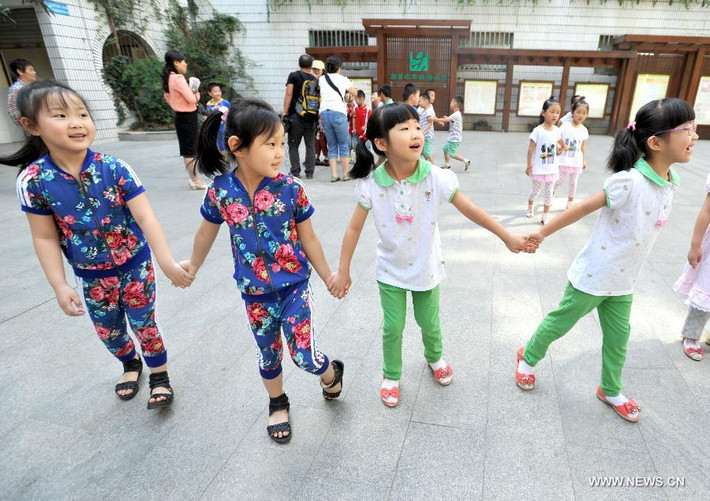 Hai cặp song sinh vui vẻ nắm tay nhau chơi đùa trong ngày tựu trường.