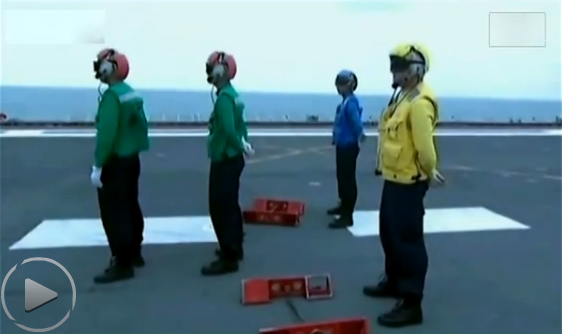 Các thủy thủ tàu sân bay Liêu ninh Trung Quốc đội mũ bảo hiểm, mặc quần áo màu xanh dương, xanh lá cây và vàng chuẩn bị làm nhiệm vụ chỉ hướng cho chiến đấu cơ J-15.