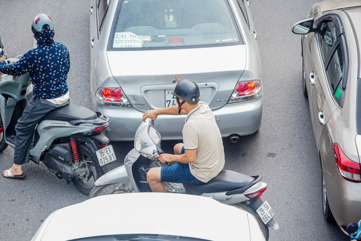 Xe máy luồn lách giữa hai ô tô.