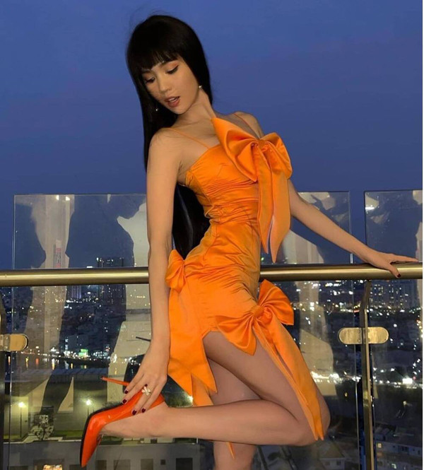 So với những bộ đồ trước, người đẹp gốc Trà Vinh nữ tính hơn hẳn trong bộ váy cam với họa tiết nơ.
