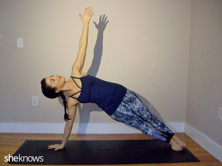 Động tác Side plank. Dùng tay trái nâng cơ thể lên cao và lấy chân làm trụ cho cơ thể, tay phải giơ lên cao vuông góc cơ thể. Cố gắng giữ tư thế này trong 5 – 10 phút. Động tác này tăng cường cơ bắp ở tay, bụng và chân, đồng thời siết chặt vùng eo, hông và giãn cơ khoeo bắp chân. Ảnh: Sheknows.