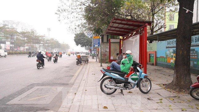 Những người hoạt động trong lĩnh vực xe ôm công nghệ ngồi chờ khách tại 1 bến xe buýt.