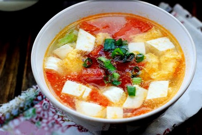 Đầu tiên đun nóng dầu rồi phi thơm hành tím. Khi hành tím dậy mùi cho cà chua vào đảo nhẹ tay. Khi cà chua mềm cho nước và gia vị vừa ăn vào. Đun sôi cho mềm cà chua thì thả đậu phụ vào. Chờ đến khi canh sôi trở lại, nêm gia vị vừa miệng, cho thêm hành, ngò vào là được. Ảnh: Baophunu.