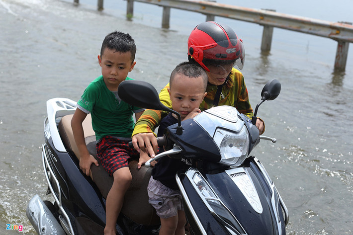 Một phụ nữ chở hai em bé xe bị chết máy phải dắt bộ chặng đường khá dài. Những đoạn ngập sâu chị cũng bị loạng choạng tay lái.