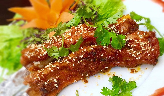 Rạch đường chéo song song vào phần thịt sườn đã rửa sạch rồi ướp với sa tế, hạt tiêu, mật ong, hành khô, nước mắm, dầu oliu trong 20 phút. Nướng sườn trên bếp than hoa đến khi sườn dần ngả sang màu cánh gián là được. Ảnh: ElinerFood.com.
