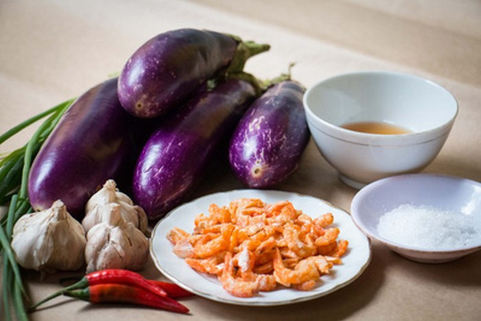1. Cà tím xào tôm. Nguyên liệu gồm cà tím, tôm khô hoặc tôm tươi, hành, tỏi, gia vị. Cà tím cắt khúc vừa ăn, tôm khô ngâm nước cho mềm, nếu là tôm tươi thì làm sạch. Tỏi và hành bóc vỏ đập dập băm nhỏ. Bắc chảo lên bếp phi thơm hành tỏi cho vàng thơm rồi cho tôm vào xào, đảo đều tay. Ảnh: Healthplus.