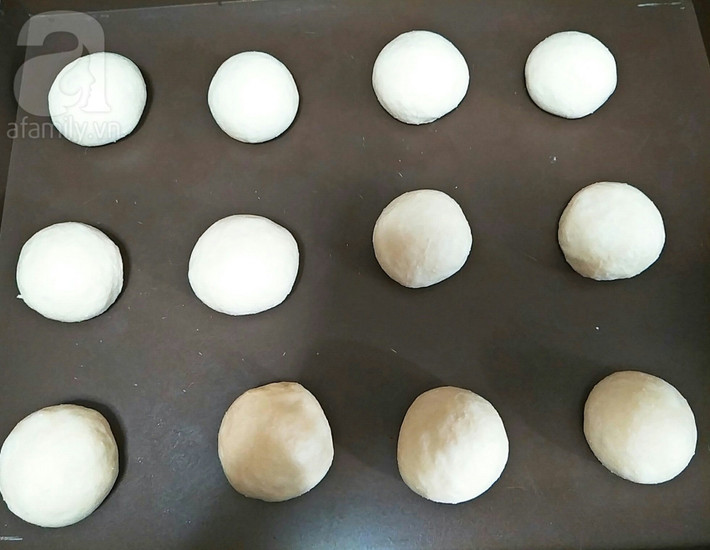 Lấy ra ấn cho xẹp bọt khí và chia đều thành những phần bằng nhau sau đó vê tròn, đặt lên khay ủ tiếp 10 phút. Sau khi ủ đủ thời gian, lấy viên bột cán mỏng vừa, cho phô mai vào và bọc kín vo tròn không cho nhân bị hở. Ảnh: aFamily.vn.