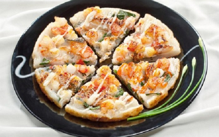 Bắc chảo lên bếp, cho dầu vào. Khi dầu sôi thì cho 1 muỗng bột vào, dàn đều. Sau đó, bạn trải các loại hải sản lên trên cùng với ớt tươi. Đổ 1/3 lượng trứng lên trên phần nhân hải sản. Chiên bánh với mức lửa vừa từ 2 – 3 phút rồi dùng muôi dẹt lật mặt bánh, chiên tiếp khoảng 2-3 phút nữa. Khi bánh chín đều 2 mặt là hoàn thành món bánh. Ảnh: Cachlam9.