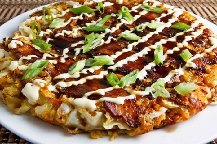 Cho dầu vào chảo, đun nóng ở nhiệt độ 200 độ C thì bắt đầu múc hỗn hợp bánh xèo vào chảo. Xếp thịt đã thái sẵn lên trên bánh chiên khỏang 3p thì lật mặt bánh chiên thêm 5p nữa cho tới khi 2 mặt bánh vàng đều và phần trong chín hẳn. Khi bánh đã chín phết đều nuớc sốt bánh xèo, mayonnaise và hành lá lên mặt trên của bánh. Thêm rong biển và cá vụn cho bánh thêm phần bắt mắt. Ảnh: Hokkaidoshusi.