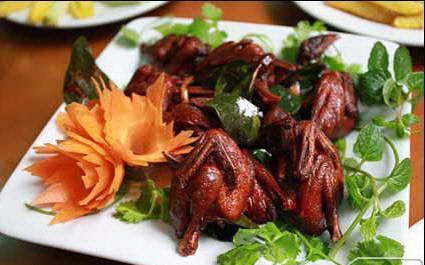 Làm nóng dầu hào trong chảo, cho chim cút đã ướp gia vị vào, chiên vàng đều. Khi chim cút chín, gắp ra đĩa có lót sẵn giấy nến để thấm dầu. Trộn đều hành tây với hạt nêm, đường trắng, giấm, tiêu trong 1 cái chén. Xếp xà lách ra đĩa, thêm cà chua và chim cút chiên lên trên. Cuối cùng chỉ việc rưới đều hành tây đã trộn vào là xong. Ảnh: Vietnamesefood.com.