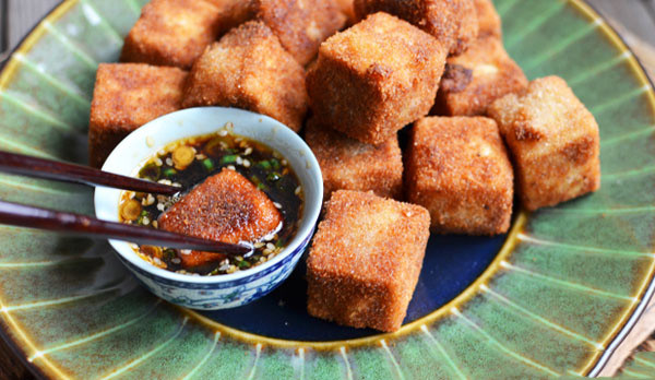 Trộn bột bắp và bột ngũ vị hương vào 1 cái đĩa. Sau đó, nhúng đậu hũ non vào hỗn hợp bột bắp, đến trứng gà rồi qua 1 lớp bột chiên xù. Làm nóng dầu ăn trong chảo, cho đậu hũ non vào, chiên giòn. Thỉnh thoảng lật đều để đậu hũ không bị cháy. Ăn đậu với cơm và chấm kèm nước tương hoặc tương ớt sẽ ngon hơn. Ảnh: aFamily.vn.