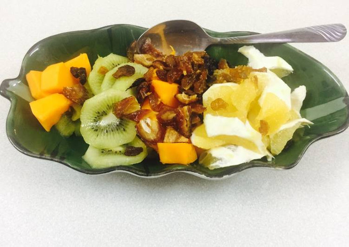 3. Thuyền trái cây. Nguyên liệu: Cam, kiwi, đu đủ, chà là, nho khô, mứt cóc gừng thái nhỏ. Gọt vỏ cam và kiwi, đu đủ thái lát. Chà là dùng kéo cắt nhỏ bằng nho khô. Trộn đều các trái cây và khi ăn thì dùng thìa lấy chung các loại trái cây để ăn cho hoà chung các vị của trái cây tươi, khô. Ảnh: cookpad.com.