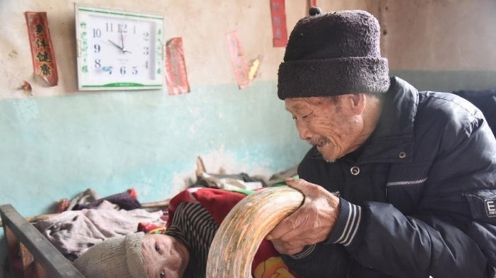 Mỗi khi nghe đồn có thuốc thảo dược nào chữa được là ông lại lên núi tìm thuốc về sắc. Trước khi cho vợ uống, ông cũng đều thử trước vì sợ vợ uống phải độc tố. Cứ như vậy, 2 ông bà sống trong căn nhà nhỏ không con cháu. Ông lụi cụi sắc thuốc, đút từng muỗng cháo cho vợ. Ảnh: Elitedaily.