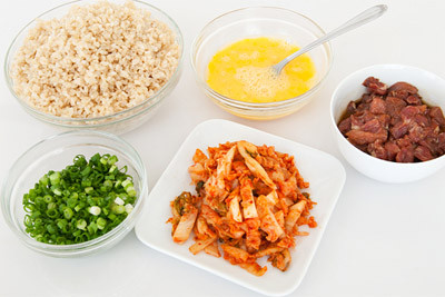 6. Cơm rang kim chi. Nguyên liệu: Cơm nguội, kim chi cải thảo, trứng, hành, tỏi, dầu vừng, vừng trắng rang chín, hành lá, dầu ăn, xì dầu, dầu hào. Cơm đánh tơi. Kim chi vắt khô nước, thái miếng nhỏ. Trứng đập, đánh đều. Phi thơm hành tỏi, cho cơm vào đảo đều, rưới trứng lên trên và đảo nhanh tay 3 phút. Ảnh: gianbepla.com.