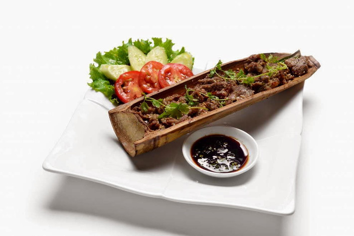 Nướng trên than hoa khoảng 15-20 phút. Khi thịt chín ta chẻ một phần ống tre để lộ phần thịt. Cho ống tre nướng thịt lên đĩa, rắc rau mùi và tiêu lên và ăn nóng. Chuẩn bị thêm muối ớt hoặc xì dầu để chấm thịt. Ảnh: imonanngon.info.