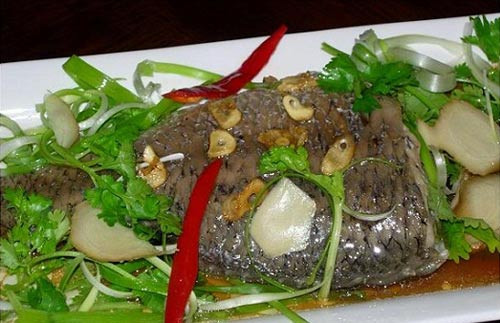 Hòa tan 2 thìa đường vào 2 muỗng canh nước mắm rồi rưới đều lên cá, sau đó cho thêm gừng đã thái sợi vào và hấp trong 5 phút. Cho tỏi băm đã phi thơm, hành lá thái khúc rồi cho vào nồi cá đang hấp. Ảnh: nghethuatamthuc.vn.
