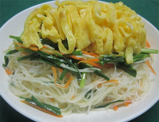 Cho mỳ vào chảo dầu đảo đều, cho 1 thìa bột nêm vừa ăn sau đó cho cà rốt vào xào cùng, đến khi mỳ chín thì cho hành vào. Cho bún xào ra dĩa, xếp rau, trứng lên mặt. Có thể ăn bún gạo xào với nước mắm hoặc nước tương pha chua ngọt. Ảnh: toinayangi.vn.