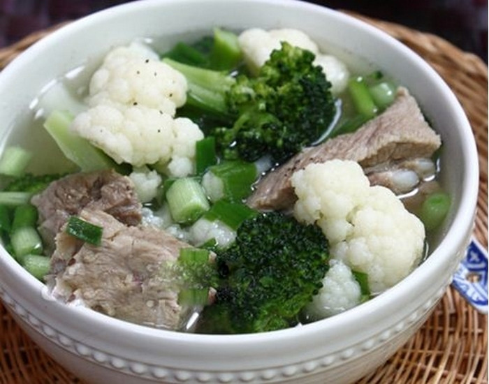 Sườn mềm, cho hai loại súp lơ vào nồi, nêm 1 thìa nhỏ nước mắm, 1/2 thìa nhỏ muối. Vì súp lơ và sườn đều rất ngọt nên bạn không cần nêm nếm nhiều gia vị tạo ngọt như hạt nêm hay mì chính nữa. Đậy vung đun khoảng 2-3 phút rồi nêm nếm lại tùy theo khẩu vị của bạn, rắc hành lá, rau mùi đã thái nhỏ vào nồi. Ảnh: Giadinh.
