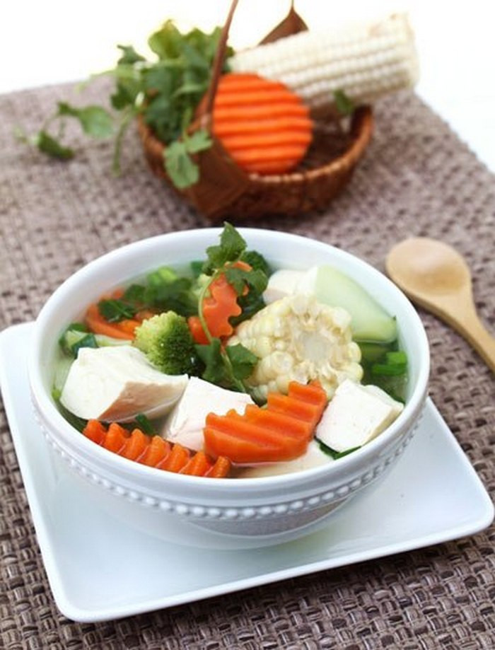Đầu tiên hãy thái các nguyên liệu trên, chú ý không cắt đậu quá nhỏ để đậu vẫn giữ được miếng đẹp. Cho ngôi vào đun sôi trước, khi ngô mềm thì đổ su su và cà rốt vào đun đến khi nhừ. Tiếp theo cho súp lơ, nêm gia vị vừa ăn. Tiếp theo là thả đậu phụ vào đun tầm 3 phút. Tắt bếp, rắc hành mùi vào là đã có món canh ngon tuyệt. Ảnh: Anngon.