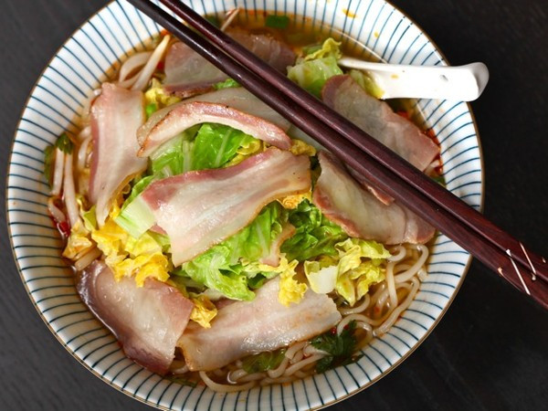 Cho thêm một vài lát thịt hun khói: Cho 2 lát thịt hun khói cắt thành từng miếng vừa ăn và một vài lá bắp cải thái nhỏ vào nồi khoảng 2 phút trước khi mỳ chín. Ảnh: HaVietfoods.vn.
