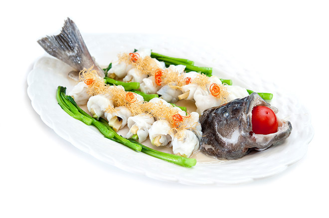 Đặt đầu và xương cá chẽm vào đĩa lớn, xếp các cuộn cá xung quanh. Rưới dầu mè lên. Hấp cách thủy với gừng tươi và sả cây 30 phút. Làm nước chấm cá với xì dầu, đường, bột ngọt, ớt trái. Sau khi cá chín, xếp lên trên đĩa cải thìa sốt dầu hào, rải sả chiên giòn lên trên các cuộn cá. Cho cà chua bi vào miệng hay xung quanh cá. Ảnh: zing.news.vn.