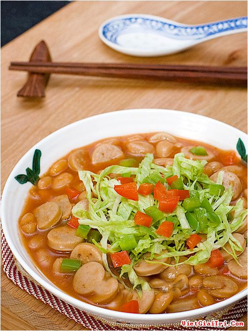 Dùng muỗng để trộn xúc xích và đậu nướng cho tốt. Cho ớt chuông vào bát và để trong lò vi sóng trong vòng 2 phút. Trộn một nửa số ớt chín vào hỗn hợp, sau đó trang trí món ăn với rau diếp và ớt thái nhỏ. Ăn với cơm sẽ rất ngon. Ảnh: Vietgiaitri.com.