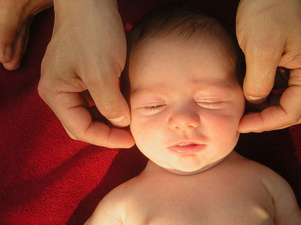 Sau đó, mẹ hãy dùng ngón tay cái xoay thành những vòng tròn nhỏ theo chiều kim đồng hồ những xung quanh hàm và đằng sau tai bé để đưa bé vào giấc ngủ. Ảnh: HoiBacSi.com.