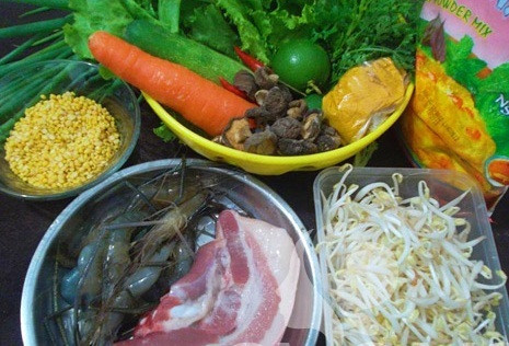 Đậu xanh ngâm nước khoảng 30 phút rồi hấp chín. Bắc chảo lên bếp cho nóng rồi láng đều bột bánh xèo. Lắc đều để bột trải đều khắp chảo. Xếp lên bề mặt bánh một vài con tôm, thịt, thêm đỗ xanh, giá đỗ, cà rốt. Cuối cùng cho bông điên điển vào và đậy kín nắp chảo lại. Đun lửa lớn từ 3-4 phút dùng muôi gấp bánh xèo làm đôi, rán đến khi phần vỏ vừa ý thì tắt bếp gắp bánh xèo ra đĩa. Ảnh: Vaobepnauan.