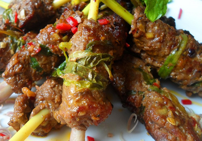 Bò khi ướp xong lấy ra tay rồi đặt 1-2 lát hành tây lên, rồi để cây sả vô giữa, cuộn lại. Cuộn chặt rồi lấy tăm ghim để khỏi bị bung. Thái hành lá vào 1 cái bát con nhỏ, sau đó đem đun sôi dầu ăn, rồi đổ vào bát hành lá, làm như vậy ta sẽ được bát mỡ hành. Xếp bò lên bếp nướng than hoa không khói nướng đều các mặt, vừa nướng vừa phết mỡ hành để thịt không khô. Ảnh: NiemDamMe.Vn.