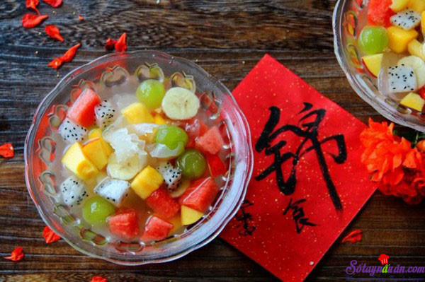Đào, chuối, nho, thanh long và xoài các bạn bỏ vỏ rồi cắt thành miếng nhỏ. Dưa hấu, bạn cắt bỏ vỏ rồi cắt thành miếng hạt lựu. Các bạn lần lượt cho nho, chuối, dưa hấu, xoài, đào, thanh long vào nồi nước đã để nguội, khuấy đều lên rồi múc ra bát thưởng thức. Ảnh: sotaynauan.com.