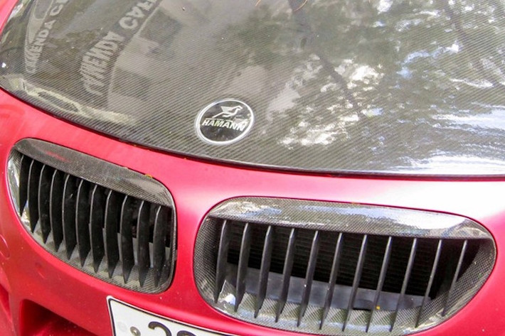 Một số món "đồ chơi" bằng sợi carbon từ Hamann như lưới tản nhiệt và nắp ca-pô cũng khiến chiếc xe trở nên nổi bật hơn và tạo điểm nhấn trên thân xe đỏ mờ.