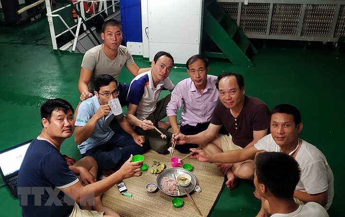 Hào hứng thưởng thức món gỏi cá ngay trên boong tàu. (Ảnh: Hoàng Hùng/TTXVN)