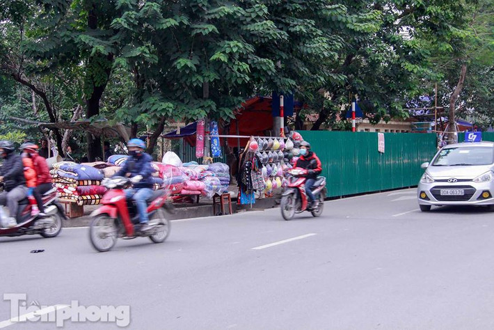Các cửa hàng vỉa hè đường Láng tranh thủ bán ngay cạnh công trình được quây rào tôn.