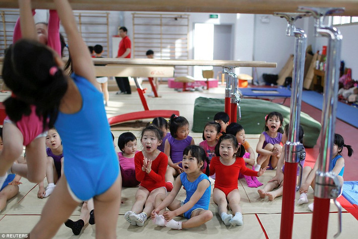 Các bé gái đang cổ vũ cho bạn trong giờ thực hành thể dục dụng cụ.