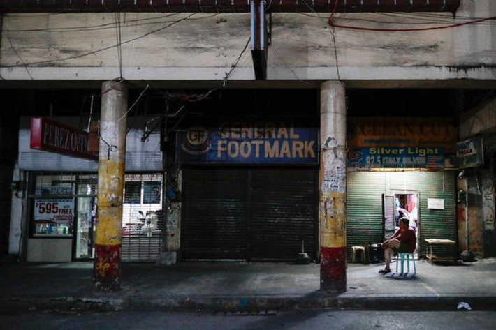 Một người đàn ông ngồi bên ngoài các cửa hàng đóng cửa ngày 24/3 sau khi Manila, thủ đô Philippines, bị đặt dưới lệnh phong tỏa.