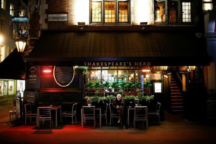 Một người đàn ông ngồi một mình bên ngoài quán rượu trên đường Carnaby ở London, Anh, ngày 17/3.