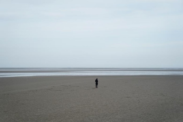 Một người phụ nữ đứng trên bờ biển Sandymount vắng người ở Dublin, Ireland, ngày 23/3.