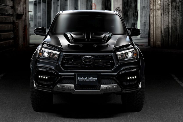 Về tổng quan, chiếc Toyota Hilux Black Bison 2020 mới của Wald toát lên một vẻ hung dữ nhờ nước sơn đen tối màu, cùng nhiều chi tiết độ như các vòm bánh cỡ lớn, bộ lốp địa hình chuyên dụng, tấm nắp gân guốc trên mui xe, và nhiều chi tiết khác.