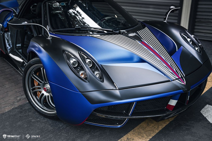 Với 2 màu là đen mờ và xanh mờ, ngoại hình của siêu phẩm Pagani Huayra còn có nhiều chi tiết thể hiện cá tính cũng như phong cách chơi xe riêng của đại gia này với logo công ty gia đình, chữ ký hay còn số 405 xuất hiện trên mui xe. Cuối cùng là phía dưới cánh gió đuôi của xe Pagani Huayra được dán màu đỏ-trắng-xanh.