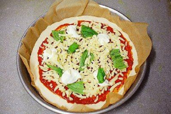 Tiếp theo rắc pho mát, rau chân vịt, có thể một ít topping kem, dầu ô liu, gia vị làm pizza và bột phô mai rồi cho vào lò nướng 180 độ trong vòng 15 phút. Trước khi nướng nhớ làm nóng lò trước nhé. (Ảnh: banh.com.vn)