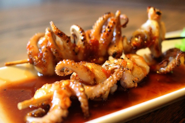 Bạch tuộc nướng. Món này vừa xuất hiện đã trở thành món ăn khoái khẩu của giới trẻ. Từ các quán ăn vỉa hè chật chội cho đến các quán ăn cao cấp đều có sự xuất hiện của món ăn này bởi thịt của nó vừa dai, vừa giòn, vừa thơm phức mùi hải sản biển. Vì bạch tuộc rất nhanh chính, nên khi nướng, người ta thường xoay que nướng liên tục để bạch tuộc không bị cháy. Bạch tuộc nướng kết hợp cùng loại nước sốt tiêu cay nồng đã làm khuynh đảo các tín đồ ăn vặt. (Ảnh: amthuc365.vn)