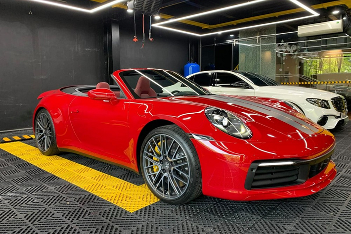 Chiếc xe Porsche 911 Carrera S Cabriolet 2021 của người chơi lan đột biến ở Bình Phước mang ngoại thất màu đỏ rất đẹp mắt, xe có thêm sọc kép màu bạc chạy dài từ nắp capô trước ra phía sau, ngoài ra là bộ mâm đa chấu kép sơn màu bạc. Chưa hết, các trang bị an toàn của xe cũng thuộc diện "hết nấc".