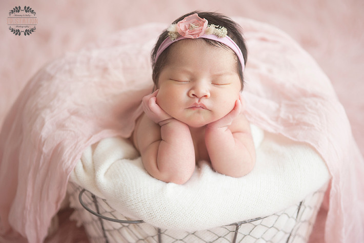 Nhiếp ảnh gia nhẹ nhàng đặt em bé trong tư thế ngồi thoải mái với tay chống cằm.