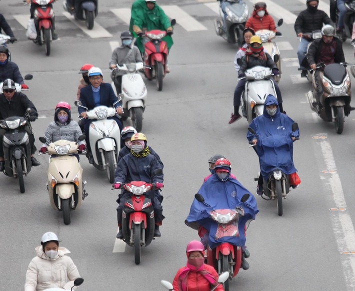 Nhiều người dân Hà Nội vẫn mặc áo mưa để chống chọi với cái lạnh dù trời không mưa.