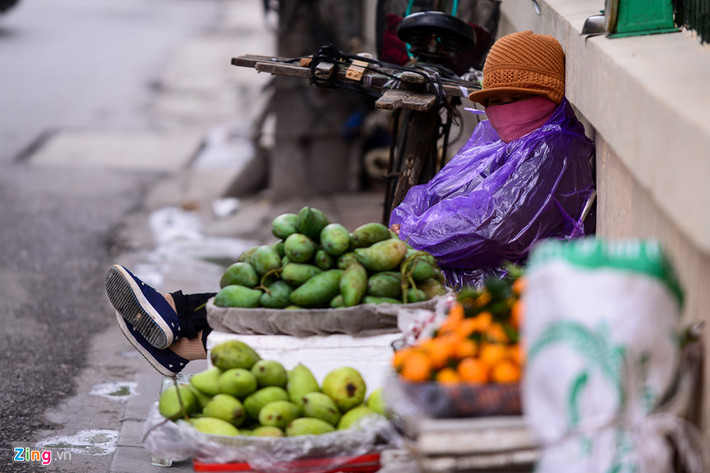 Người dân mặc áo mưa chống rét.