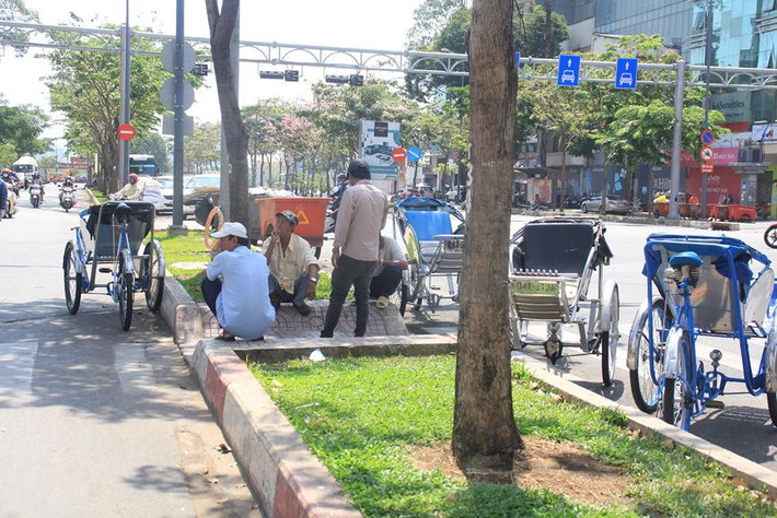Nhóm bác tài xích lô ngồi nghỉ mát dưới bóng cây trên đường Hàm Nghi, quận 1