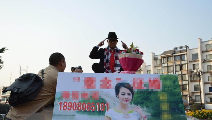 Mới đây, dư luận Trung Quốc xôn xao trước sự việc kỳ lạ xảy ra ở Quảng trường Baoguang, Thành Đô. Một người đàn ông ăn vận lịch sự, lái xe đến khu vực này rồi leo lên ngồi nóc ô tô, tay chỉ vào đầu, trước mặt là một bó hoa cùng với tấm biển tuyển vợ. Anh ta khoe thu nhập khủng của mình để thu hút sự chú ý.