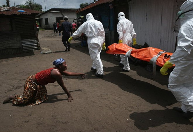 Một phụ nữ tuyệt vọng bò về phía thi thể người em bị bệnh Ebola đang được đưa đi hỏa táng.