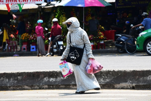 Một người phụ nữ như một con gấu bông di chuyển đường, mặc thật dày và kín là cách chống nóng hiệu quả trong những ngày này.