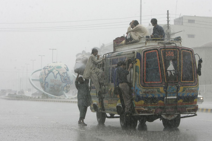 Mưa lớn không ngăn được những người đàn ông ở Karachi, Pakistan đi làm. Chiếc xe bus nhỏ không thể đủ chỗ cho họ.